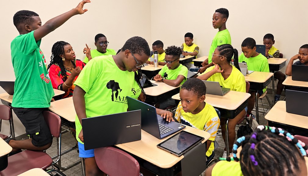 Youth in AIFS shirts working on laptops with an instructor